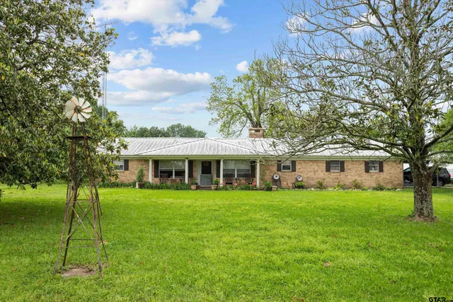 a view of a house next to a big yard and large trees