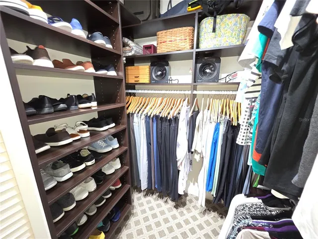 a view of walk in closet with clothes and shoes