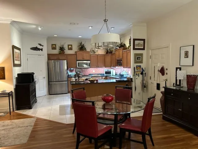 a dining hall with stainless steel appliances kitchen island granite countertop a dining table and chairs with wooden floor