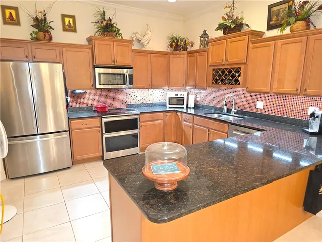 a kitchen with stainless steel appliances granite countertop a sink a stove counter space and cabinets