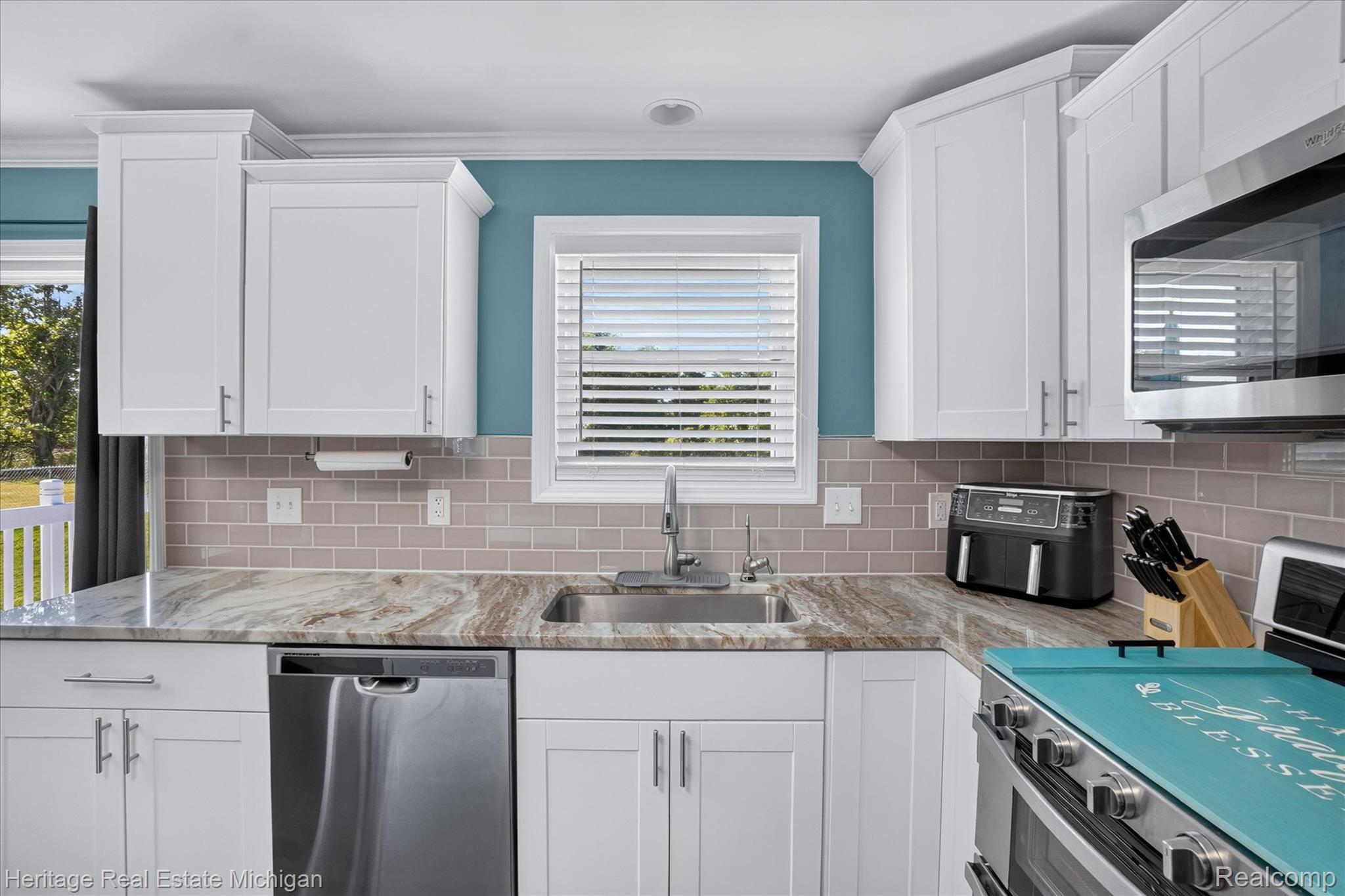 7225 Baldwin Road Swartz Creek, MI 48473 - Photo 11 of 44 Contemporary kitchen featuring white shaker cabinetry, stainless steel appliances, a subway tile backsplash, and a patterned countertop