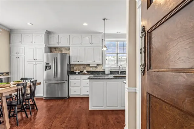 a kitchen with stainless steel appliances a refrigerator a stove top oven and a dining table with wooden floor