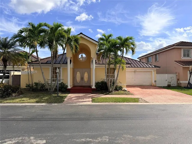 a palm tree sitting in front of a house with a yard