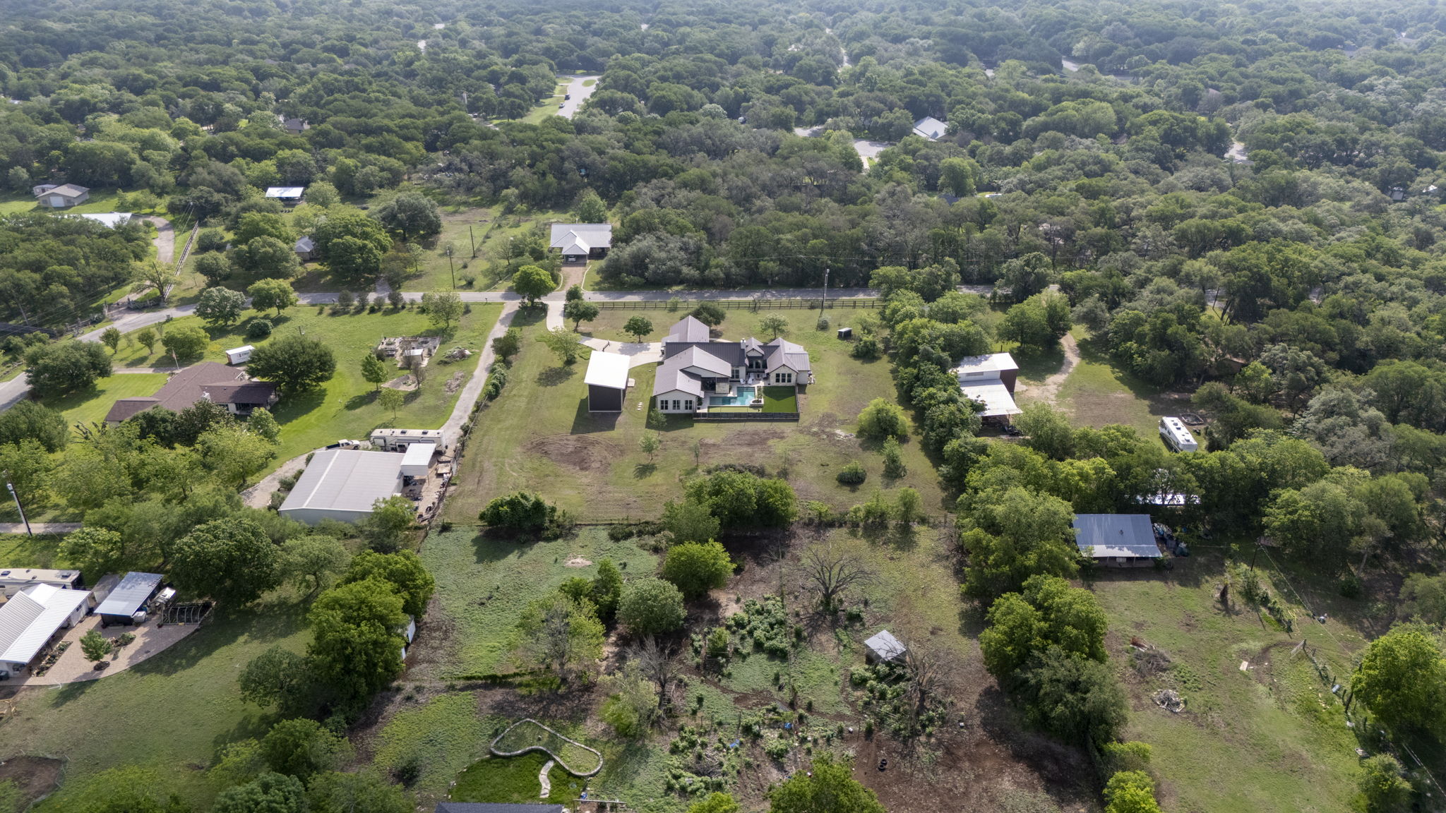 16202 Remuda Trail Buda, TX 78610 - Photo 38 of 40 The property features a large yard with a pool and is surrounded by many mature trees