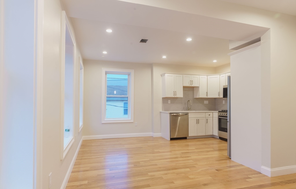 217 West 9th Street, Unit 2 Boston, MA 02127 - Photo 3 of 14 a open kitchen with kitchen island a sink wooden floor and a refrigerator