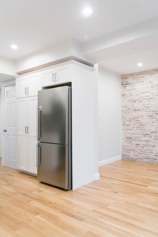 217 West 9th Street, Unit 2 Boston, MA 02127 - Photo 7 of 14 a view of an empty room with wooden floor and a kitchen