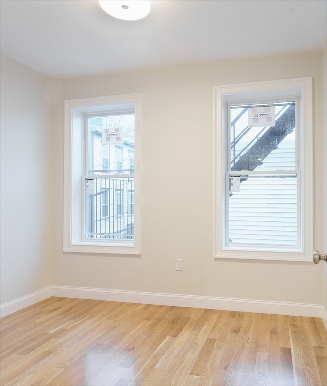 217 West 9th Street, Unit 2 Boston, MA 02127 - Photo 10 of 14 an empty room with wooden floor and windows