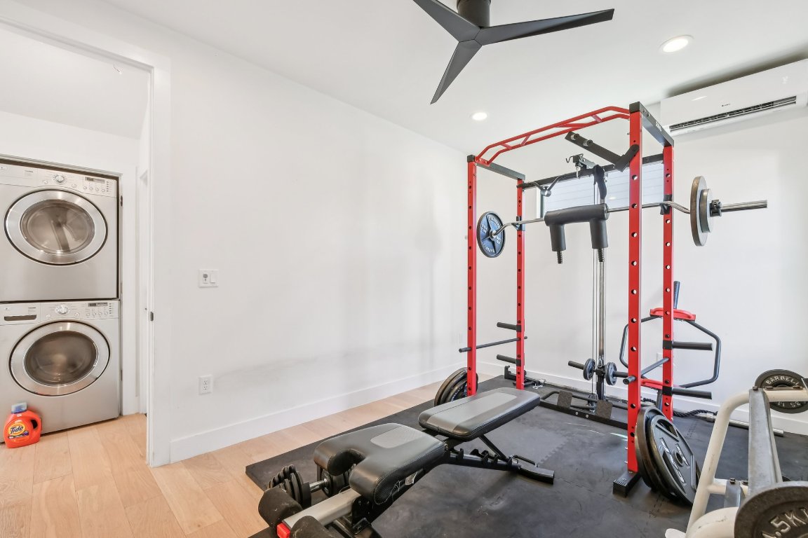 2916 East 13th Street, Unit 2 Austin, TX 78702 - Photo 23 of 35 Exercise area with estacked washer and dryer, a wall mounted AC, wood finished floors, recessed lighting, and a ceiling fan
