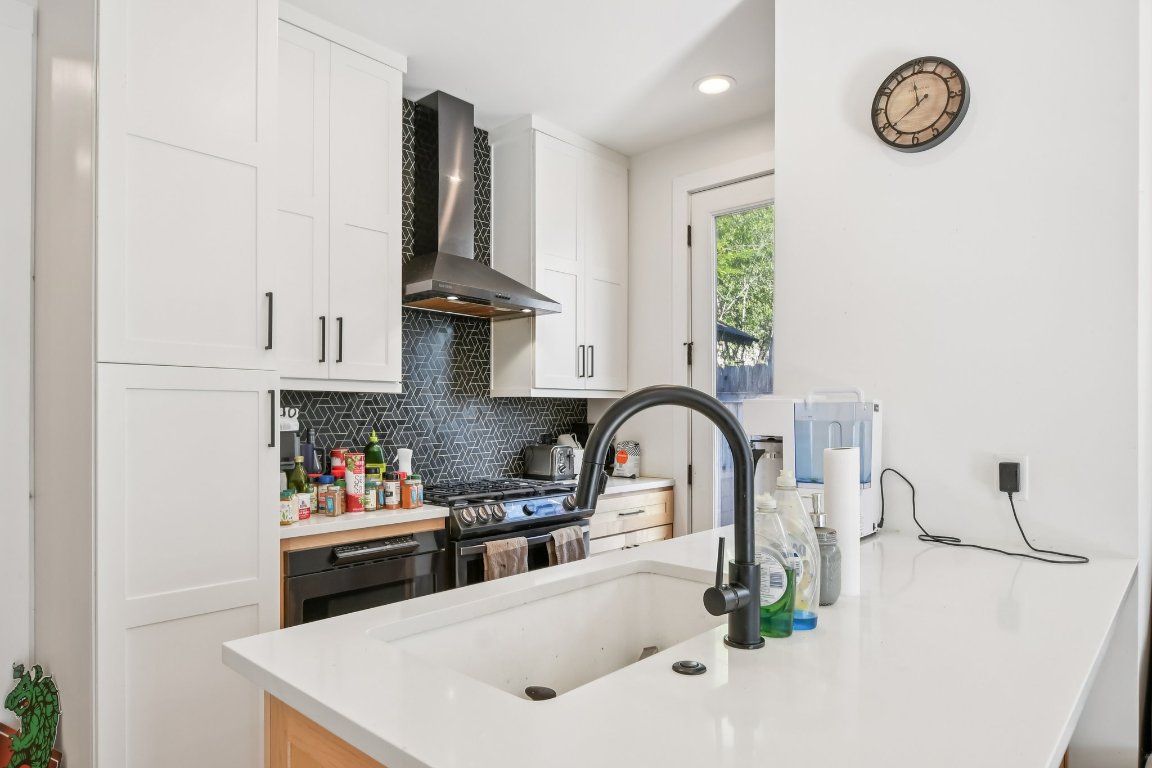 2916 East 13th Street, Unit 2 Austin, TX 78702 - Photo 7 of 35 Kitchen featuring white cabinetry, tasteful backsplash, wall chimney exhaust hood, and stainless steel gas range