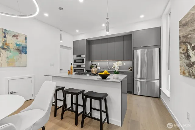 a kitchen with stainless steel appliances a refrigerator a sink a stove a dining table and chairs