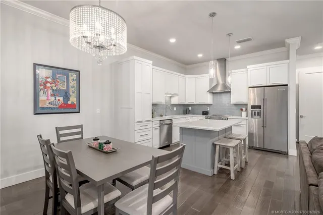 a kitchen with stainless steel appliances kitchen island a table and chairs in it