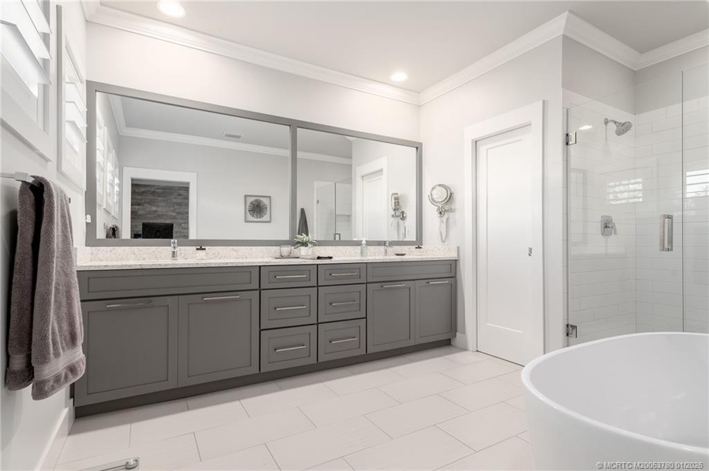 411 Southeast High School Avenue Stuart, FL 34994 - Photo 6 of 37 a spacious bathroom with a double vanity sink a mirror and a bathtub