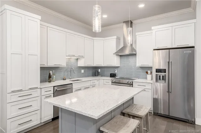 a kitchen with stainless steel appliances a refrigerator a sink dishwasher a stove and white cabinets with wooden floor