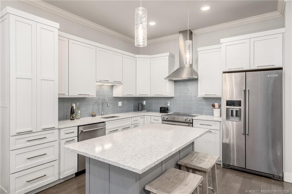 411 Southeast High School Avenue Stuart, FL 34994 - Photo 10 of 37 a kitchen with stainless steel appliances a refrigerator a sink dishwasher a stove and white cabinets with wooden floor