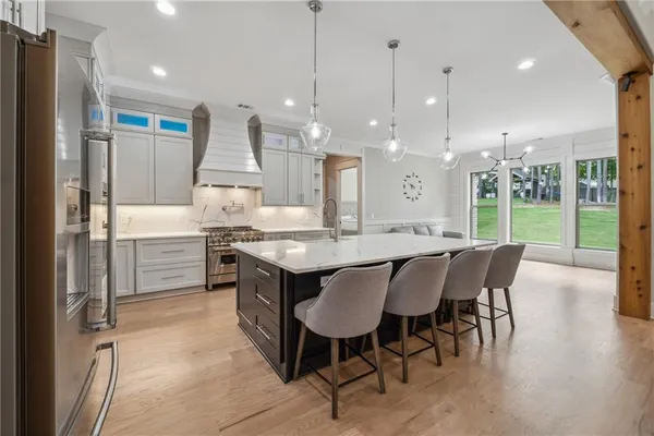 a kitchen with stainless steel appliances kitchen island granite countertop a table chairs and a refrigerator
