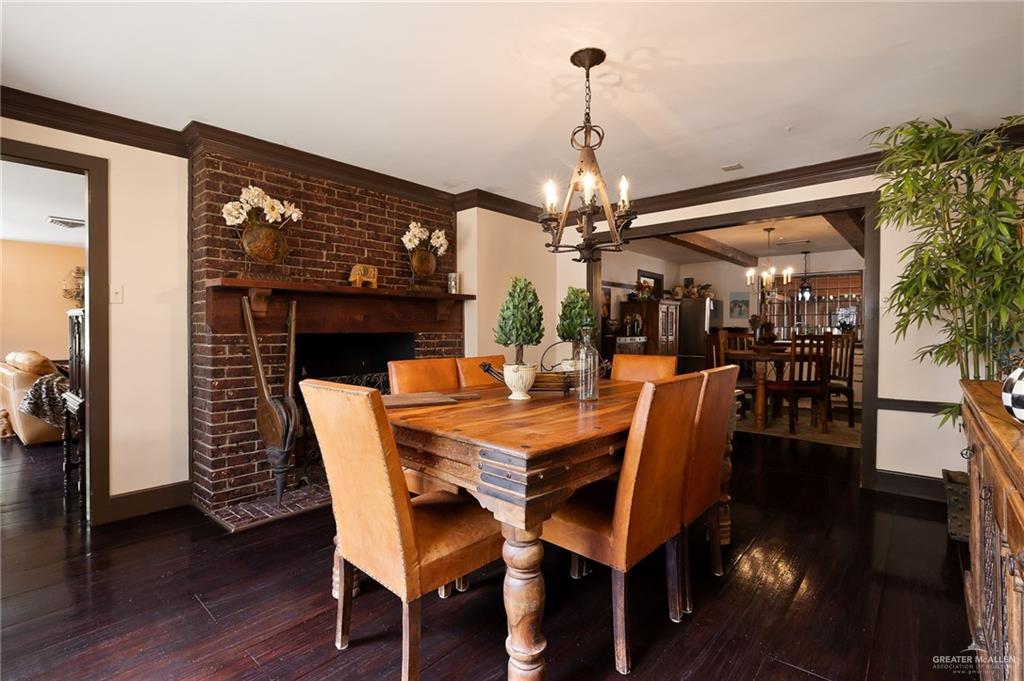 1803 North Bryan Road Mission, TX 78572 - Photo 5 of 30 Brick fireplace with wood mantel, dark wood-finish flooring, dark wood trim, and a decorative chandelier