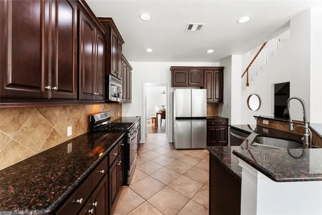 a kitchen with granite countertop a stove a sink and a refrigerator