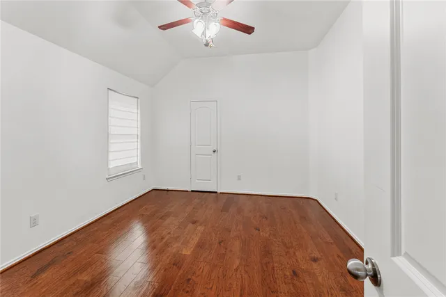 an empty room with wooden floor closet and windows