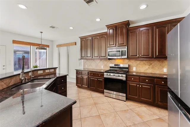a kitchen with stainless steel appliances granite countertop a sink stove and cabinets