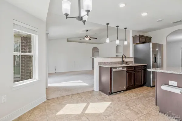 a large kitchen with stainless steel appliances kitchen island granite countertop a refrigerator and a sink