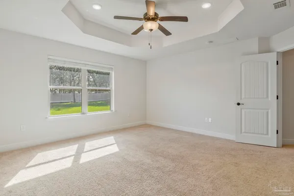 an empty room with windows and ceiling fan