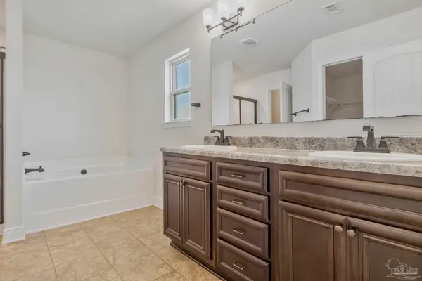 a bathroom with a sink double vanity granite tub and a mirror