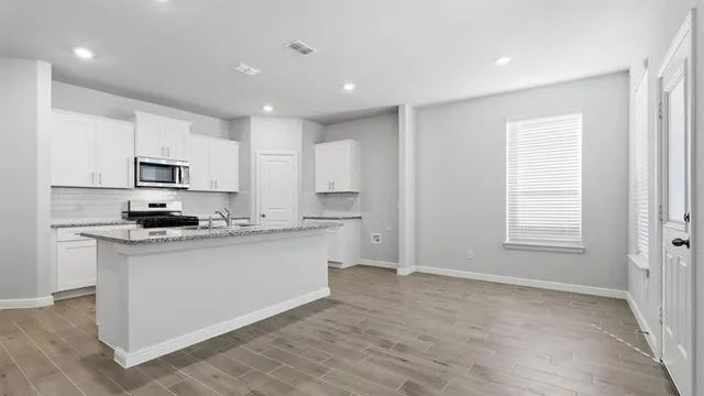 a kitchen with granite countertop white cabinets and stainless steel appliances