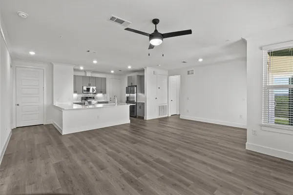 an empty room with wooden floor closet and windows