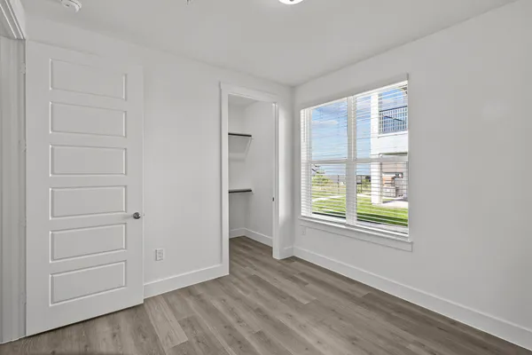 a view of an empty room with closet and a window