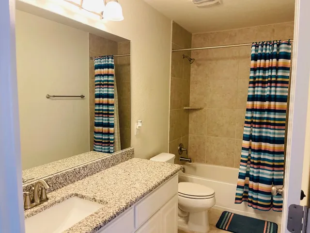 a bathroom with a granite countertop toilet sink and shower