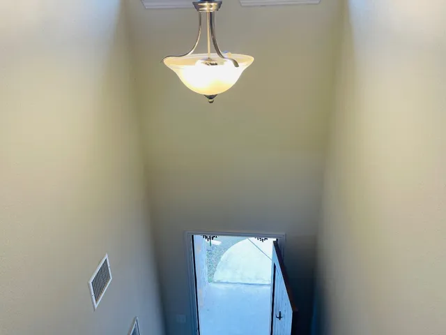 a room with a chandelier fan and a window