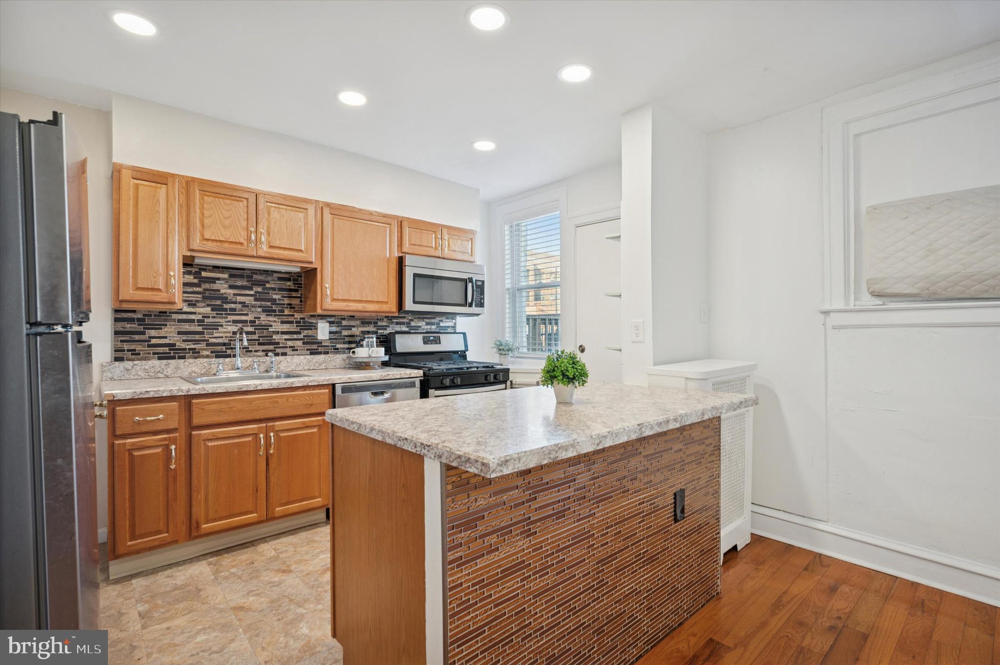 6207 Homer Street Philadelphia, PA 19144 - Photo 12 of 26 a kitchen with kitchen island granite countertop wooden cabinets and white appliances
