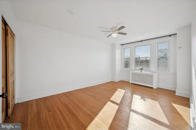 a view of empty room with wooden floor and fan