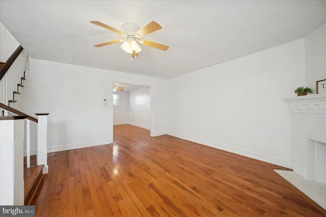 a view of an empty room with wooden floor fireplace and a window