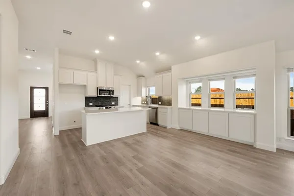 an empty room with wooden floor fireplace and windows