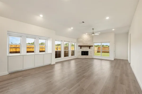 a view of an empty room with kitchen and fireplace