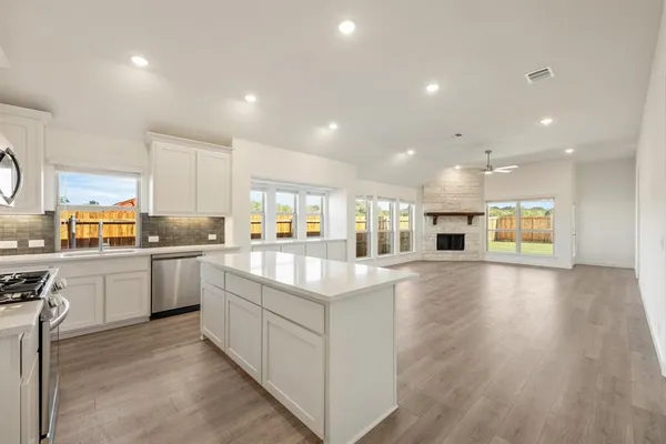 a large kitchen with stainless steel appliances granite countertop a stove a sink and white cabinets