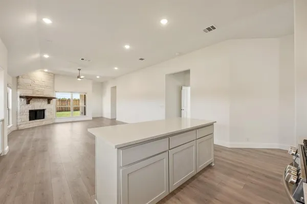 a kitchen with stainless steel appliances kitchen island granite countertop a table chairs sink and cabinets