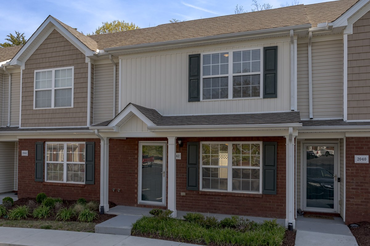 a view of a brick house with large windows and a yard