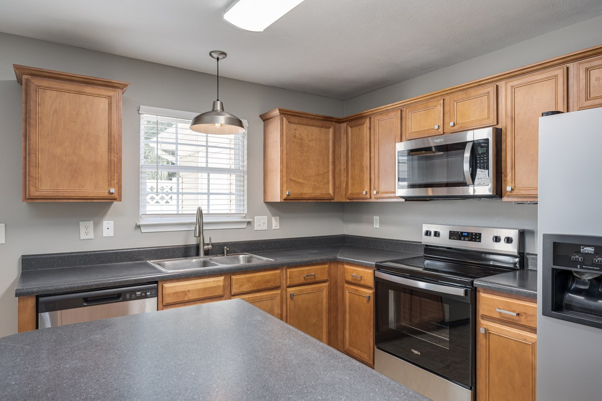 2042 Shaylin Loop Antioch, TN 37013 - Photo 17 of 54 a kitchen with stainless steel appliances granite countertop a sink a stove a microwave and wooden cabinets