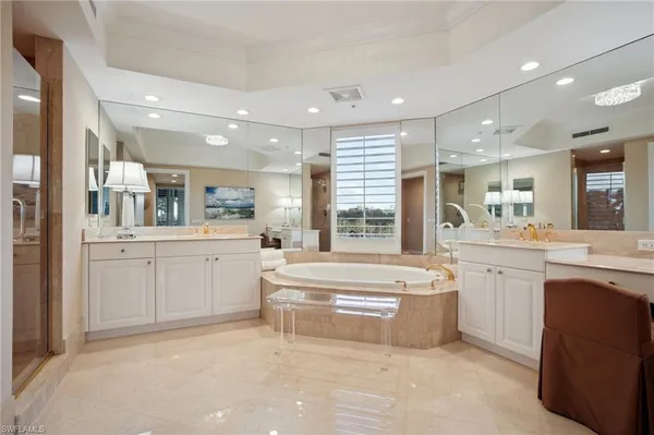 a large white bathroom with a large tub sink vanity granite and a large mirror