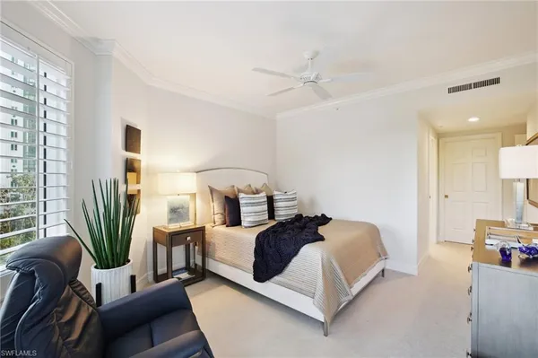 a bedroom with a bed wooden floor and a large window