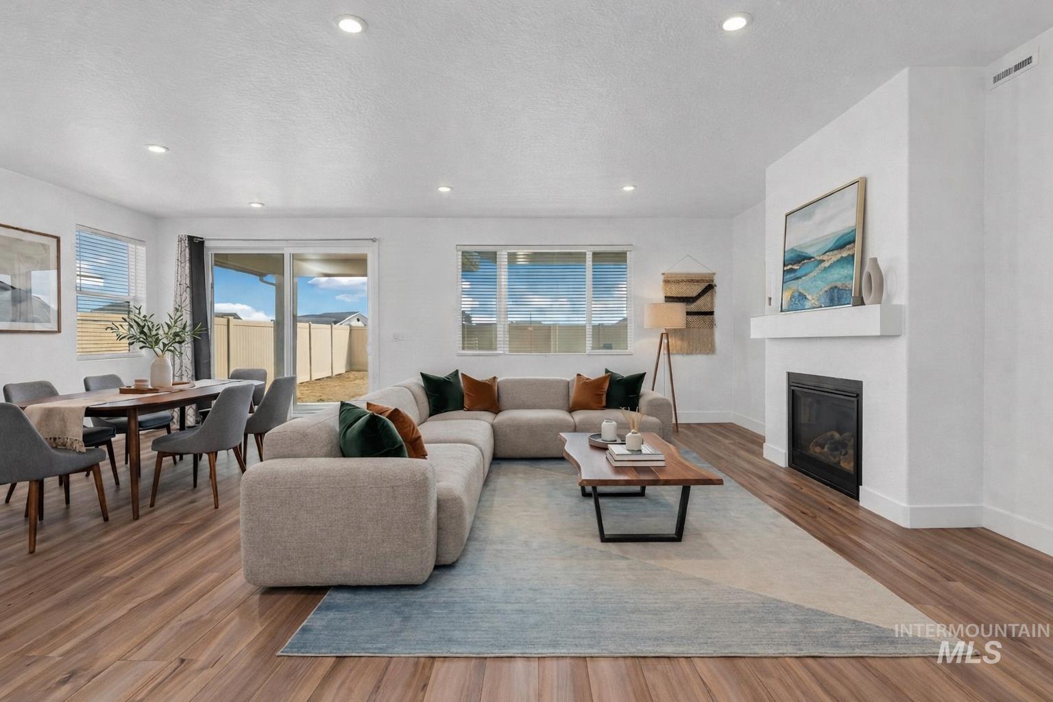 20430 Pitkin Way Caldwell, ID 83605 - Photo 3 of 23 Living room featuring wood finished floors, a glass covered fireplace, recessed lighting, and a textured ceiling