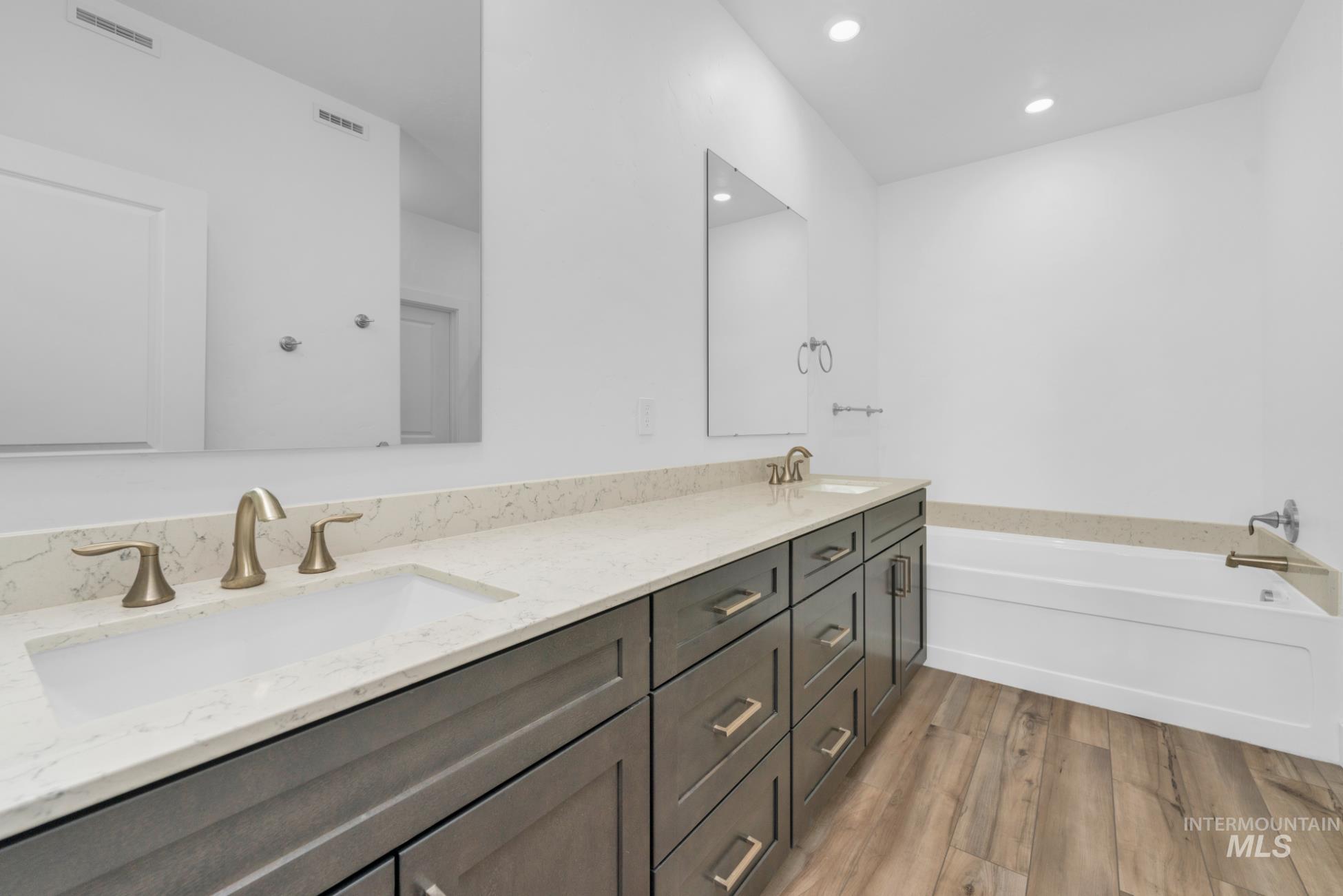 20430 Pitkin Way Caldwell, ID 83605 - Photo 8 of 23 Bathroom with double vanity, a bath, wood finished floors, and recessed lighting