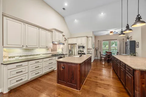 a large kitchen with kitchen island a sink a stove and a wooden floors