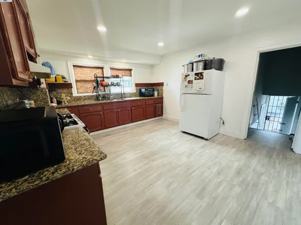 a kitchen with stainless steel appliances granite countertop a refrigerator a stove and a wooden floors