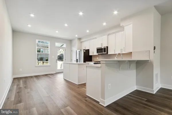 a kitchen with stainless steel appliances granite countertop a stove a sink and white cabinets with wooden floor