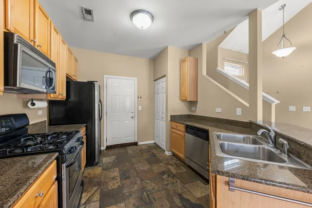 a kitchen with granite countertop stainless steel appliances a stove refrigerator and cabinets