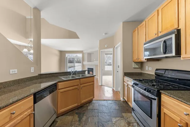 a kitchen with stainless steel appliances granite countertop a stove a sink and a microwave