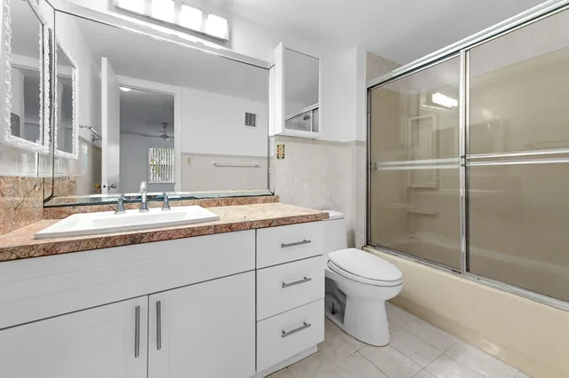 a bathroom with a granite countertop sink toilet and shower